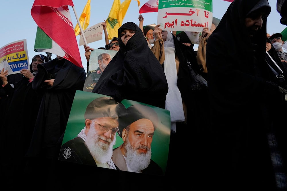 An Iranian woman holds a poster of the late revolutionary Sayyed Ruhollah Khomeini, and Leader Sayyed Ali Khamenei in an anti-US, anti-Israeli rally at Enqelab-e-Eslami square in downtown Tehran, Iran, Tuesday, June 24, 2025 (AP)