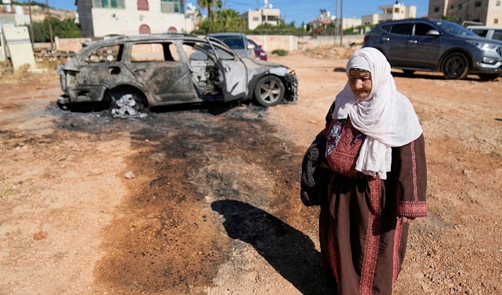 A woman walks past a vehicle that was burnt overnight by Israeli settlers in the West Bank village of Kafr Malik, east of Ramallah, Thursday, June 26, 2025. (AP)