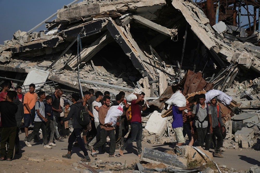 Palestinians carry humanitarian aid packages distributed by the Gaza Humanitarian Foundation, operated by the US-backed organization in Khan Younis, southern Gaza Strip, Thursday, June 26, 2025 (AP)