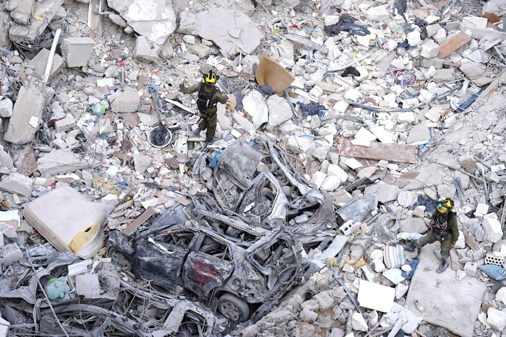 Israeli occupation soldiers search for settlers amid the rubble of buildings destroyed by an Iranian missile strike in Bat Yam, central occupied Palestine, on Sunday, June 15, 2025 (AP)