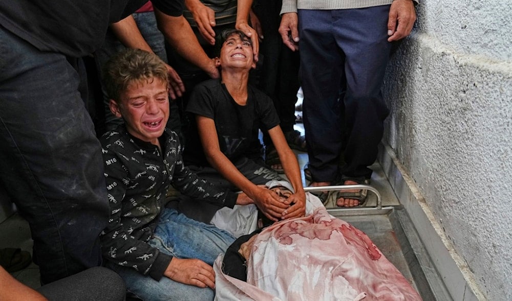 Palestinians children mourn over the body of their father, Mohammed Ghaben, who was killed while heading to an aid distribution hub, at the morgue of the Shifa Hospital in Gaza City, Wednesday, June 18, 2025. (AP)