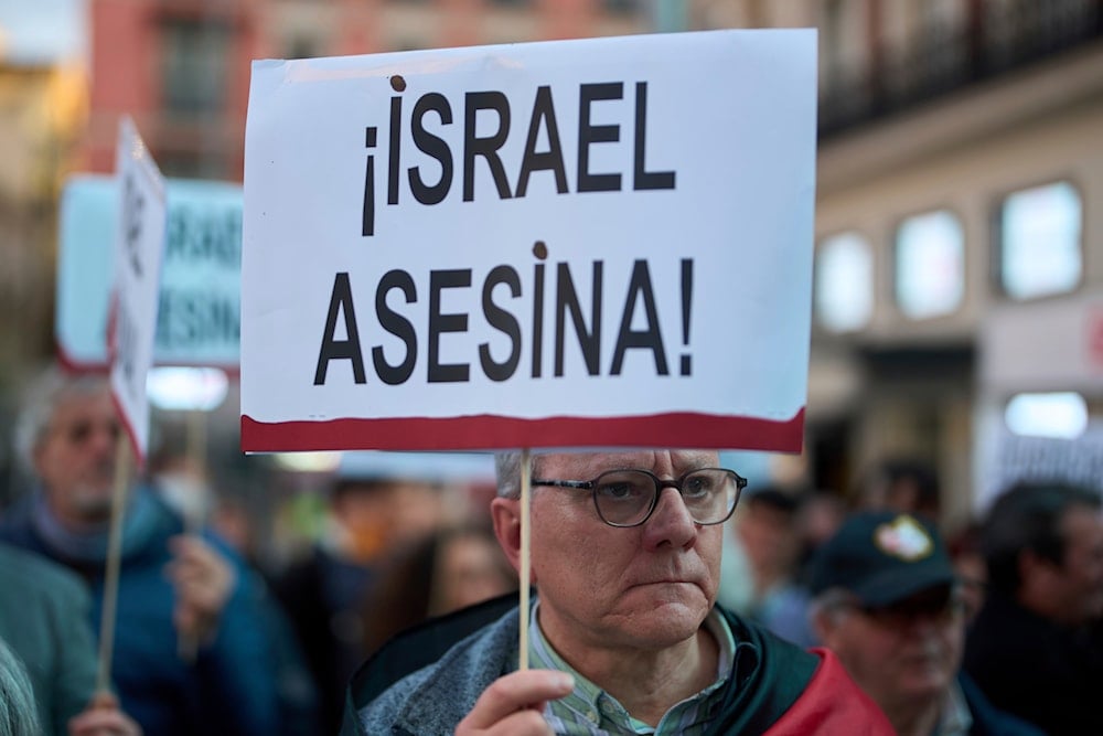 A pro-Palestinian demonstrator holds a banner reading in Spanish: 