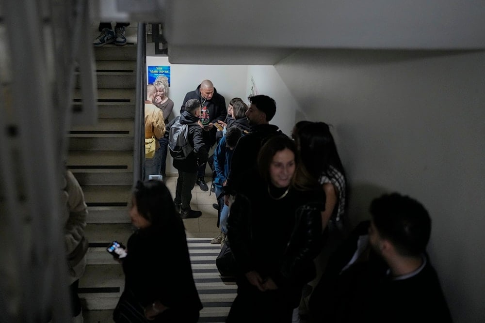 People gather in a shelter after airstrike sirens sounded off in Ben Gurion Airport, near Tel Aviv, occupied Palestine, early Friday, January 3, 2024 (AP)