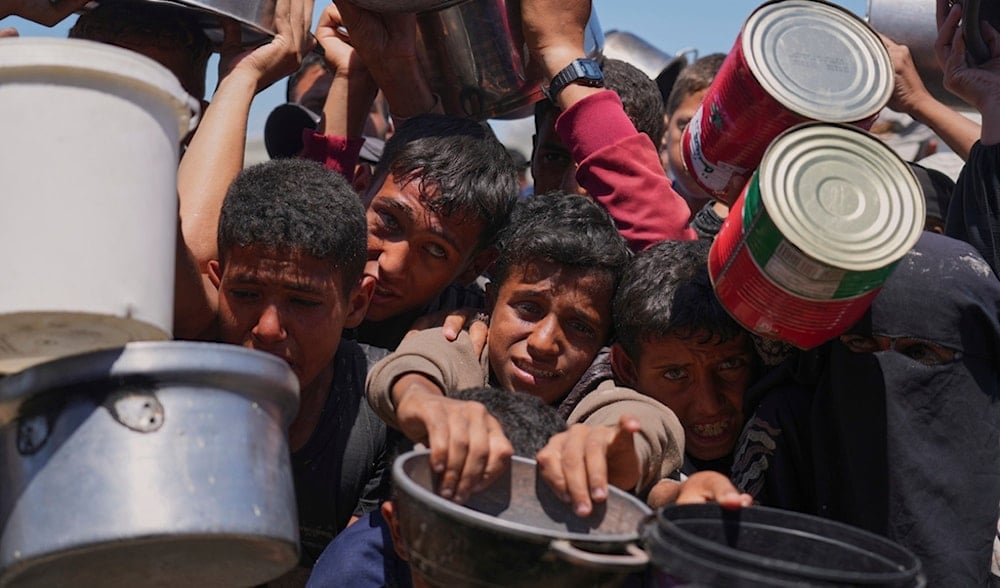 Palestinians struggle to get donated food at a community kitchen in Khan Younis, southern Gaza Strip, Monday, June 2, 2025. (AP)