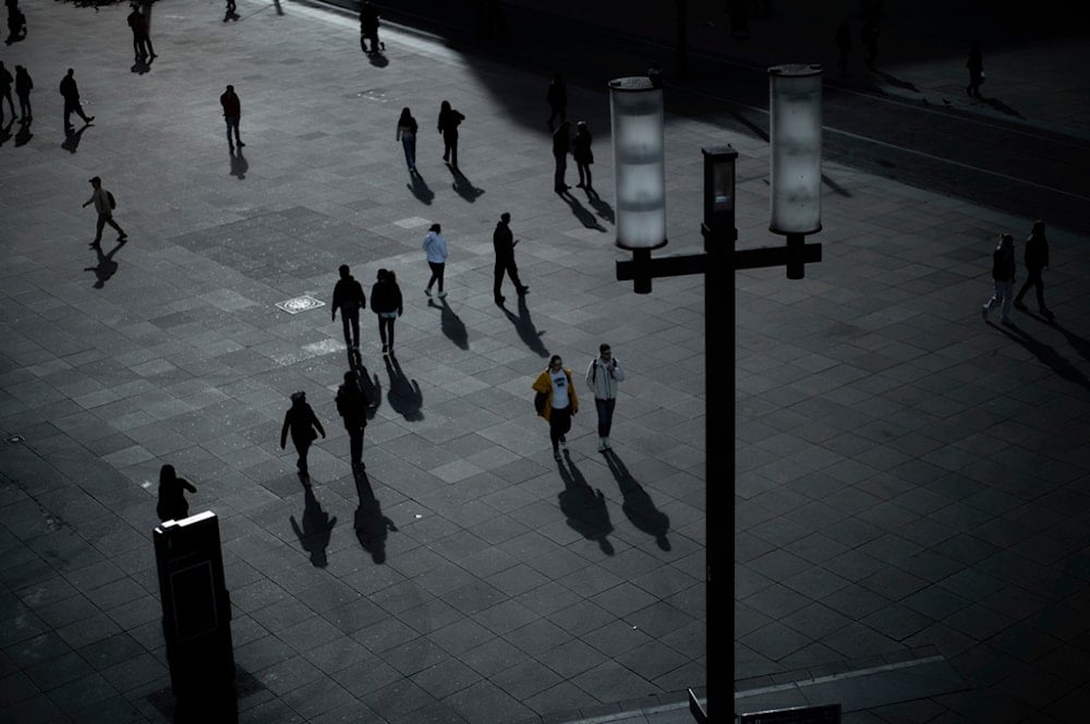 People cross Alexanderplatz, a square surrounded by warehouses and shops, in Berlin, Germany, Thursday, April 10, 2025. (AP Photo/Markus Schreiber)