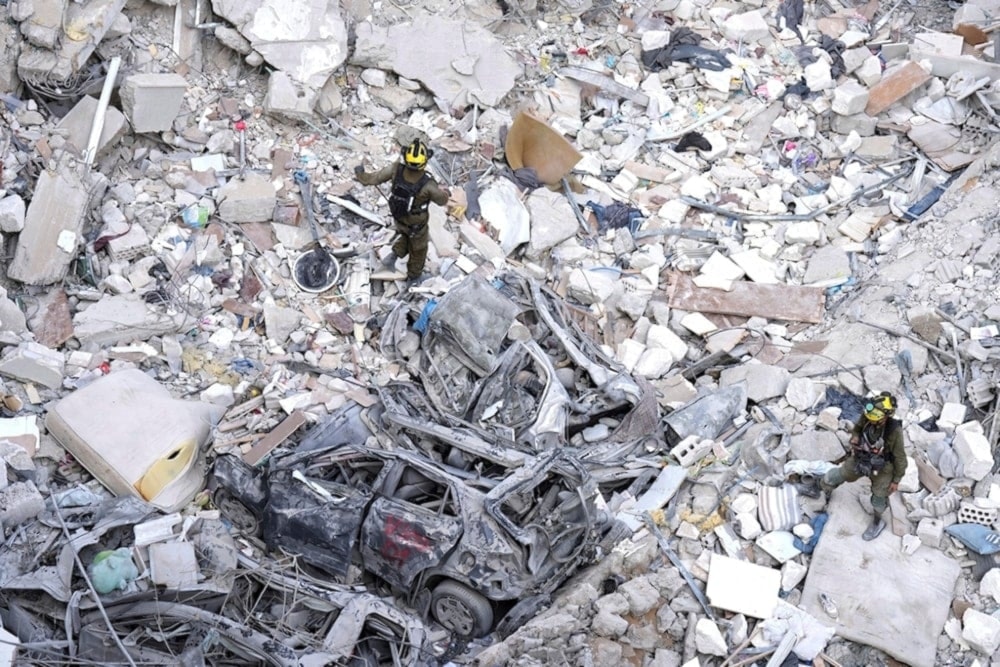 Israeli occupation soldiers search for settlers amid the rubble of buildings destroyed by an Iranian missile strike in Bat Yam, central occupied Palestine, on Sunday June 15, 2025. (AP)