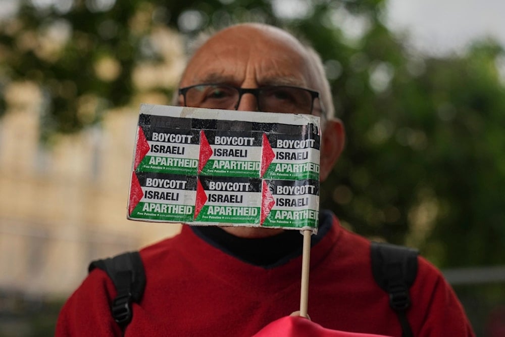 A Pro Palestinian demonstrator holds up a banner at a protest outside the Houses of Parliament during Keir Starmer's Prime Minister's Questions in London, Wednesday, June 4, 2025. (AP)