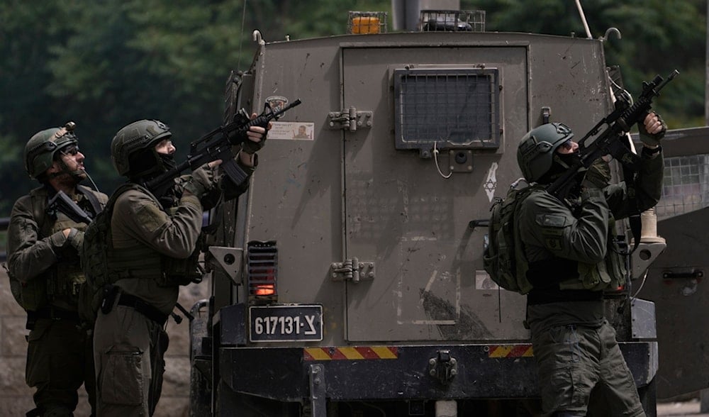 Israeli soldiers take position next to an armoured vehicle during a raid in the West Bank city of Nablus, Tuesday, May 27, 2025. (AP)