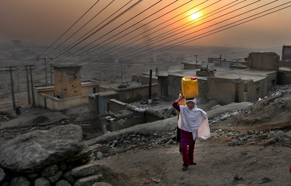 An Afghan girl carries water in a plastic container as she ascends a slope on the way towards her house in Kabul, Afghanistan, on December 27, 2010 (AP Photo/Altaf Qadri)