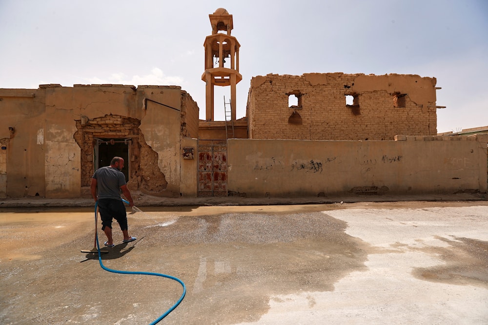 A man cleans the street beside a destroyed old church as families return to their homes after spending nine years in a notorious displacement camp in the Syrian desert, in al-Qaryatayn, in the eastern Homs province of Syria, Tuesday, June 3, 2025 (AP)