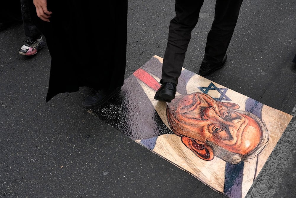 Iranian demonstrators walk on a caricature of the Israeli Prime Minister Benjamin Netanyahu during the annual Quds Day rally in support of Palestinians, in Tehran, Iran, Friday, March 28, 2025 (AP)