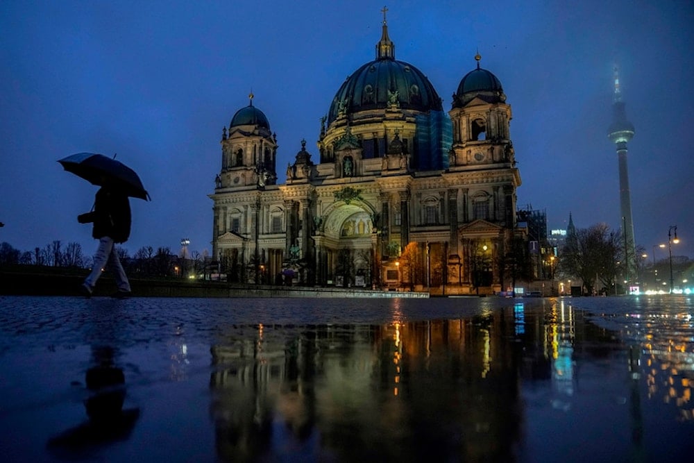People walk on the sidewalk around the Berlin Cathedral in Berlin, Germany, Friday, Feb. 28, 2025. (AP Photo/Ebrahim Noroozi)