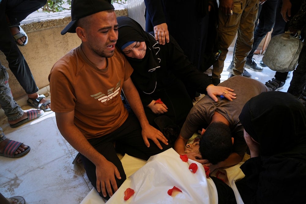 Palestinians mourn over the body of Ahmed Abu Hilal, who was killed while on his way to an aid hub in Gaza, during his funeral at Nasser Hospital in Khan Younis, in the southern Gaza Strip, on June 8, 2025. (AP Photo/Abdel Kareem Hana)
