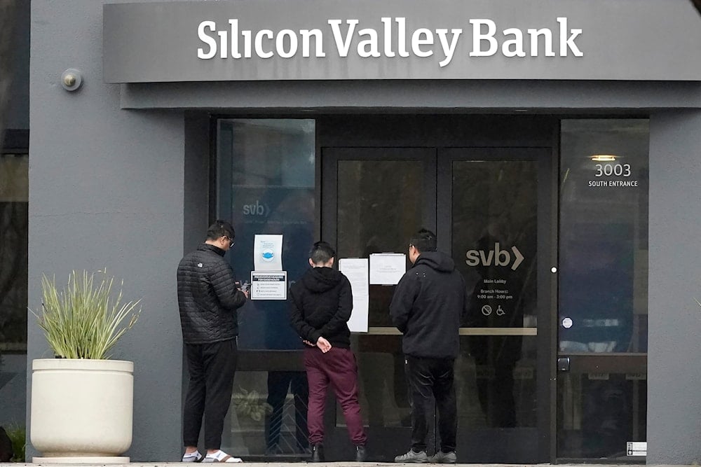 People look at signs posted outside of an entrance to Silicon Valley Bank in Santa Clara, Calif., on March 10, 2023.