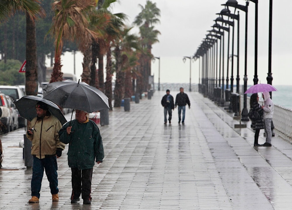 Lebanese citizens with their umbrellas walk in rainy overcast weather on the Corniche, or waterfront promenade, in Beirut, Lebanon, on Tuesday Jan. 17, 2012 (AP Photo/Hussein Malla)