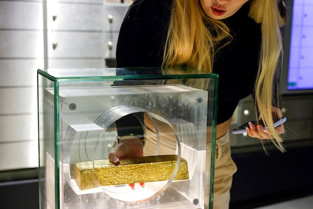 A woman lifts a gold bar at the National Bank of Poland, the country's central bank, in Warsaw, Poland, Sunday, Nov. 13, 2022. (AP)