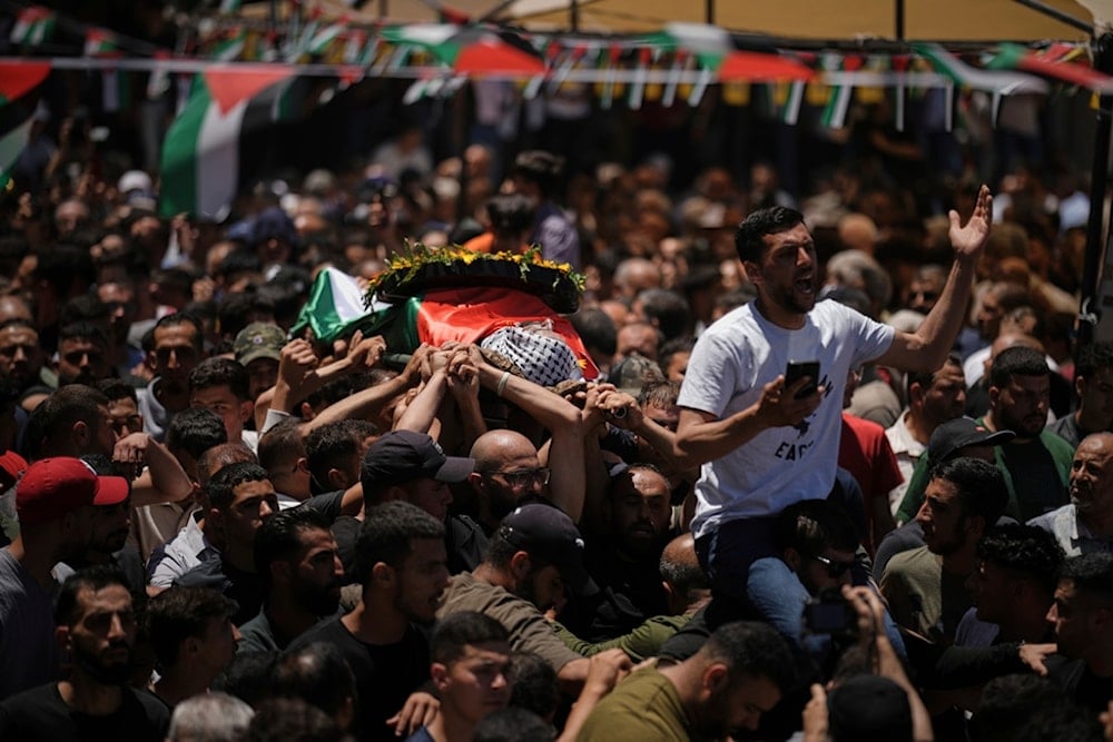 Mourners carry the bodies of martyred Palestinians during their funeral in the West Bank village of al-Mazraa a-Sharqiya on Sunday, July 13, 2025 (AP)