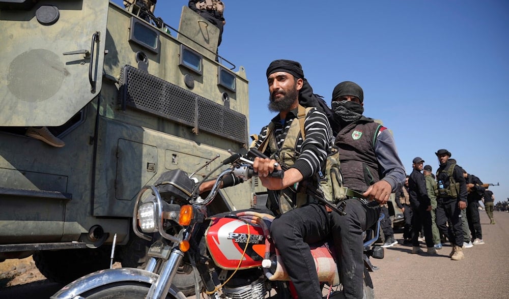 Two fighters from the Bedouin clans ride their motorcycle as they pass by Syrian government security forces deployed on the outskirts of the Sweida province, southern Syria, Monday, July 14, 2025. (AP)