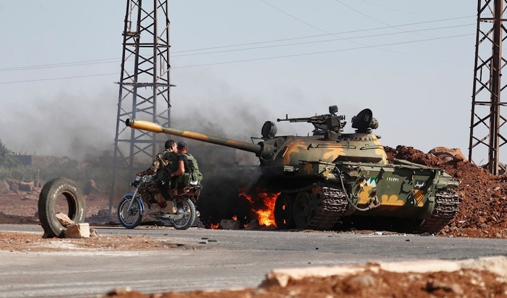 Syrian government soldiers on a motorcycle pass by a burning tank on the outskirts of Sweida city, where clashes erupted between Druze militias and Sunni Bedouin clans, in southern Syria, Monday, July 14, 2025. (AP)
