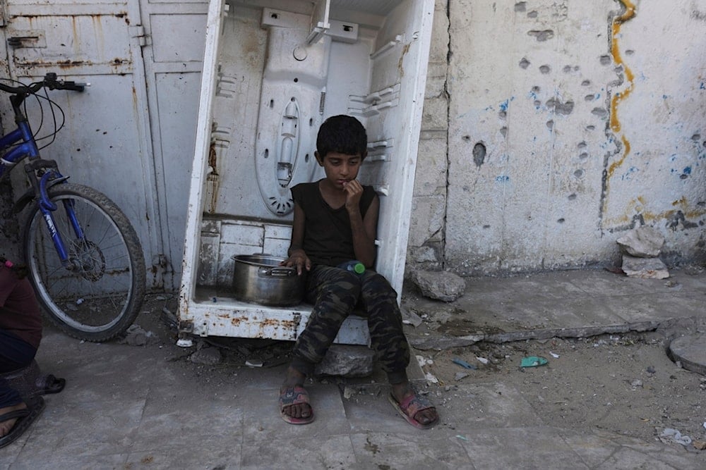 A Palestinian child waits for donated food at a community kitchen in Gaza City, in the northern Gaza Strip, Monday, July 14, 2025. (AP Photo/Jehad Alshrafi)