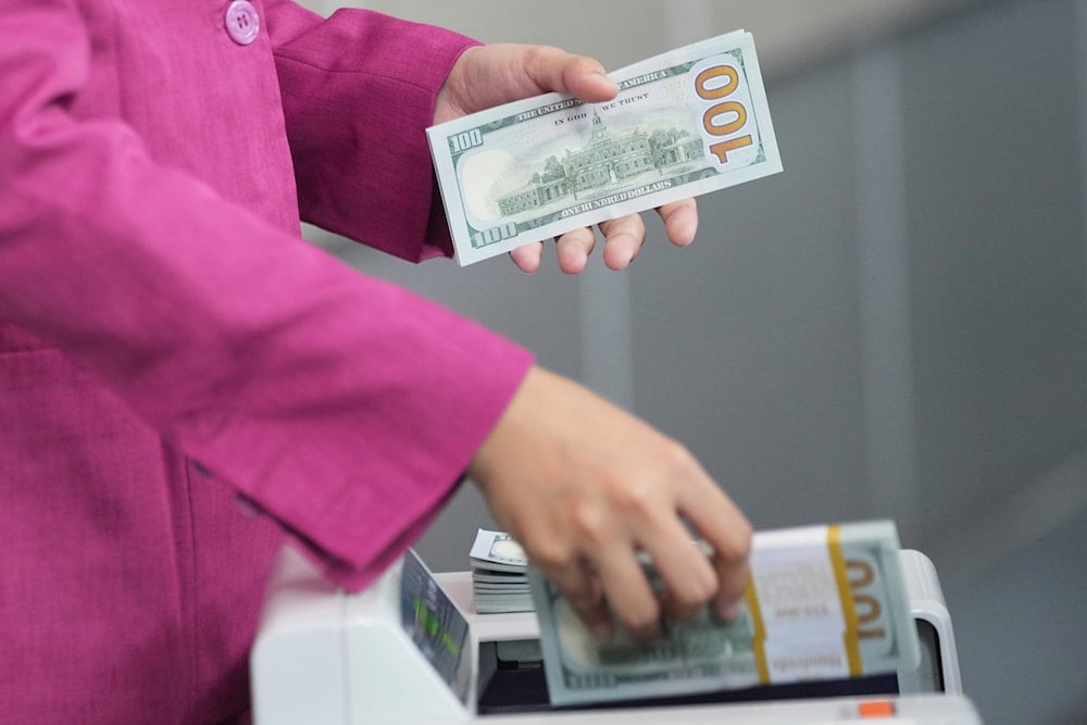An employee counts US dollar banknotes using a machine at a money changer in Jakarta, Indonesia, Tuesday, April 8, 2025. (AP)