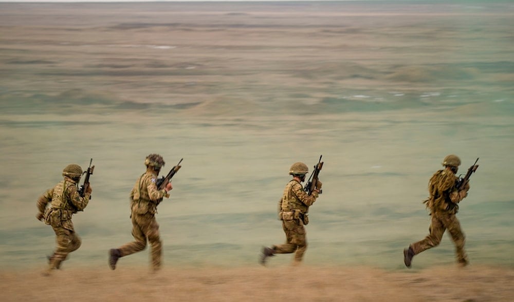 Servicemen run during the Steadfast Dart 2025 exercise, involving some 10,000 troops in three different countries from nine nations, at a training range in Smardan, eastern Romania, Feb. 19, 2025. (AP)