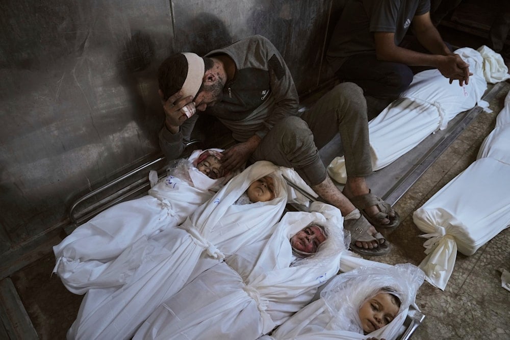 Hossam Azzam mourns over the body of his son, Amir, and other relatives who were killed in an Israeli airstrike on Gaza, at Shifa Hospital in Gaza City Tuesday, July 15, 2025 (AP)