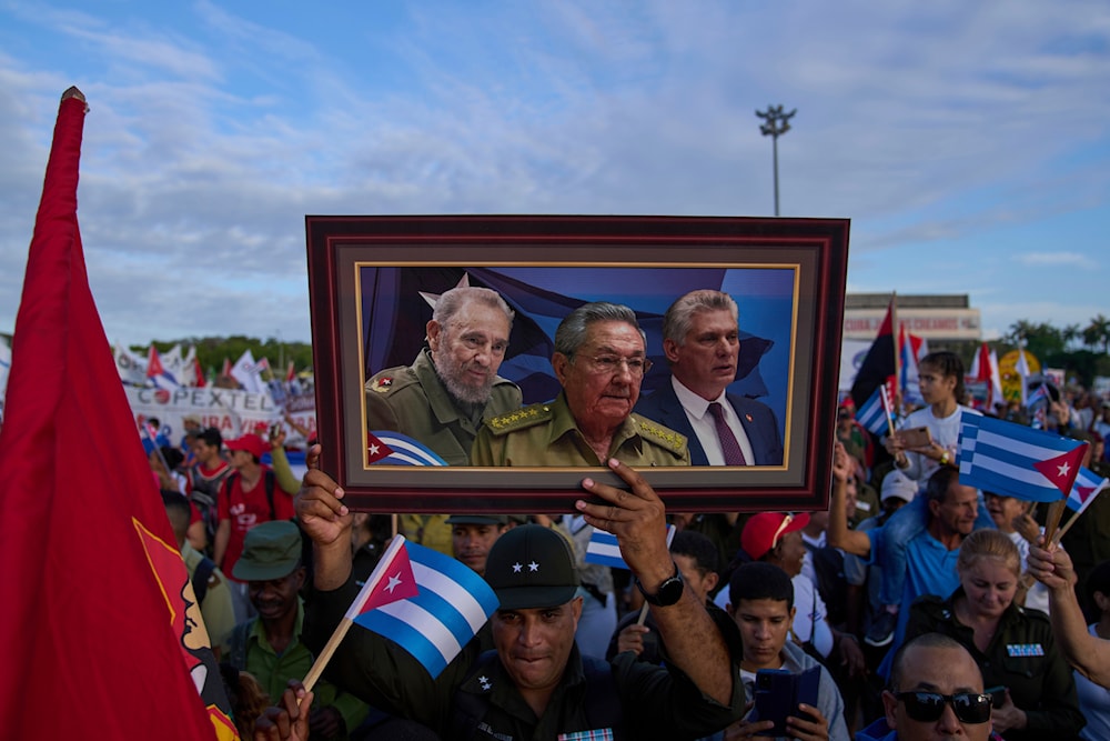 FILE - A marcher holds a framed composite image of Fidel Castro, Raul Castro and Cuba's President Miguel Diaz-Canel, during the May Day parade at Revolution Square in Havana, May 1, 2025. (AP)