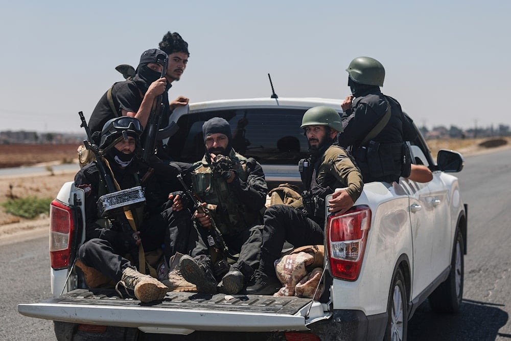 Syrian security forces ride in the back of a pickup truck on the international highway near Izraa, in rural Daraa province, Syria, Saturday, July 19, 2025 (AP)