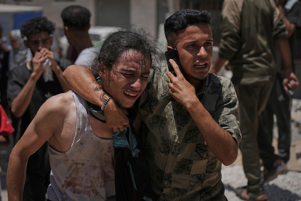 Palestinians react after carrying the bodies of those killed while trying to reach aid trucks entering northern Gaza through the Zikim crossing, at al-Shifa Hospital in Gaza City, Sunday, July 20, 2025 (AP)