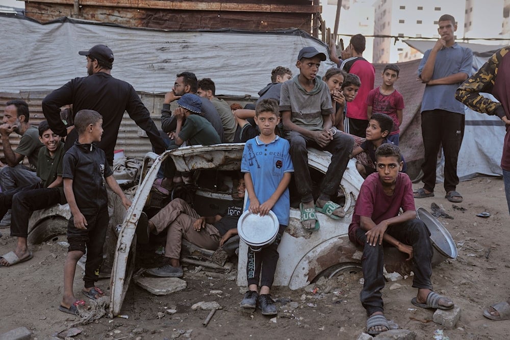 Palestinians wait for donated food at a community kitchen in Gaza City, in the northern Gaza Strip, on July 14, 2025. (AP Photo/Jehad Alshrafi)
