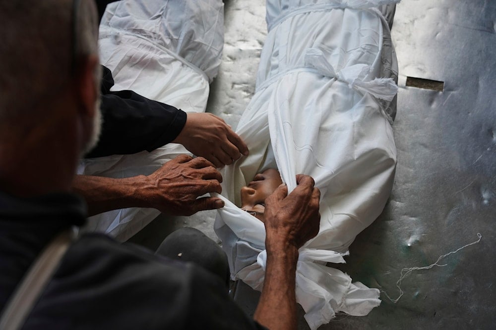 Relatives look at the body of Palestinian child Abdullah al-Rantisi, 11, killed by an Israeli military bombardment, in Deir al-Balah, central Gaza Strip, on July 21, 2025. (AP Photo/Abdel Kareem Hana)