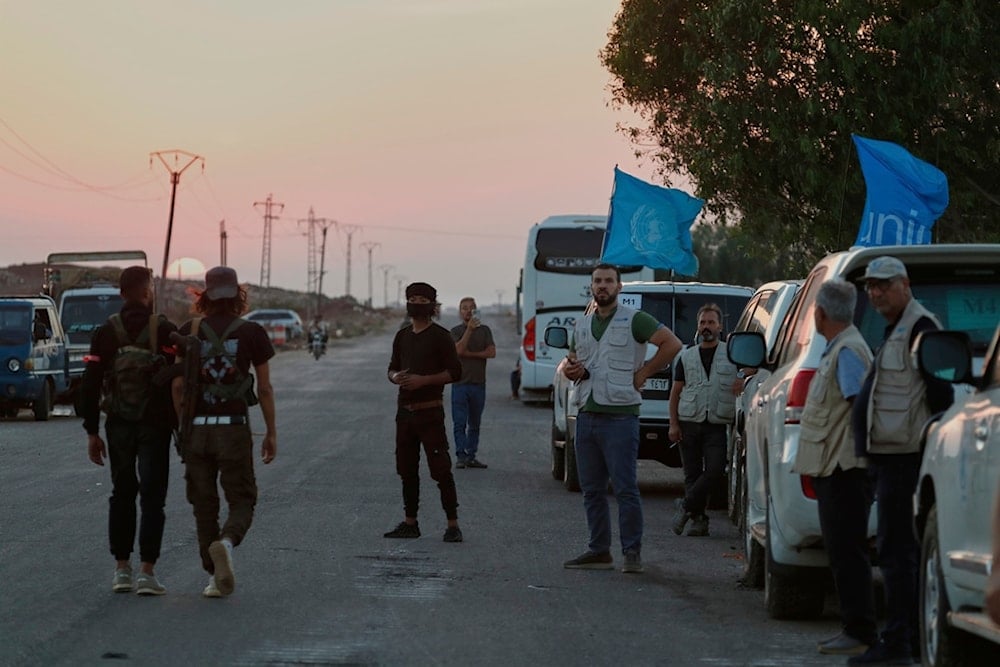 The sun sets as a convoy of ambulances and buses waits at a checkpoint in the village of Busra al-Harir, southern Syria, to enter Sweida province, Tuesday, July 22, 2025 (AP)