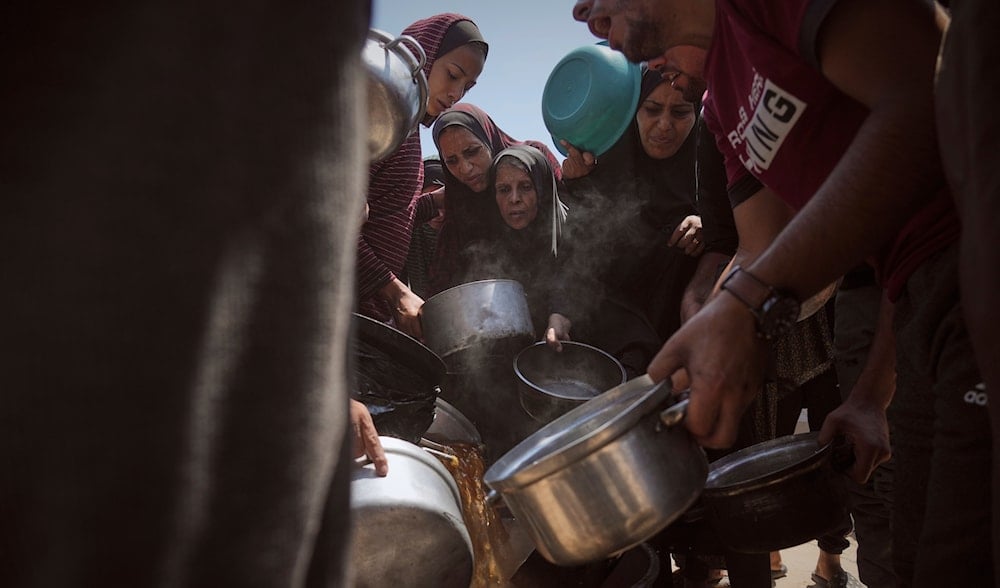 Displaced Palestinians receive donated food at a community kitchen in Gaza City, northern Gaza Strip, Tuesday, July 22, 2025. (AP)