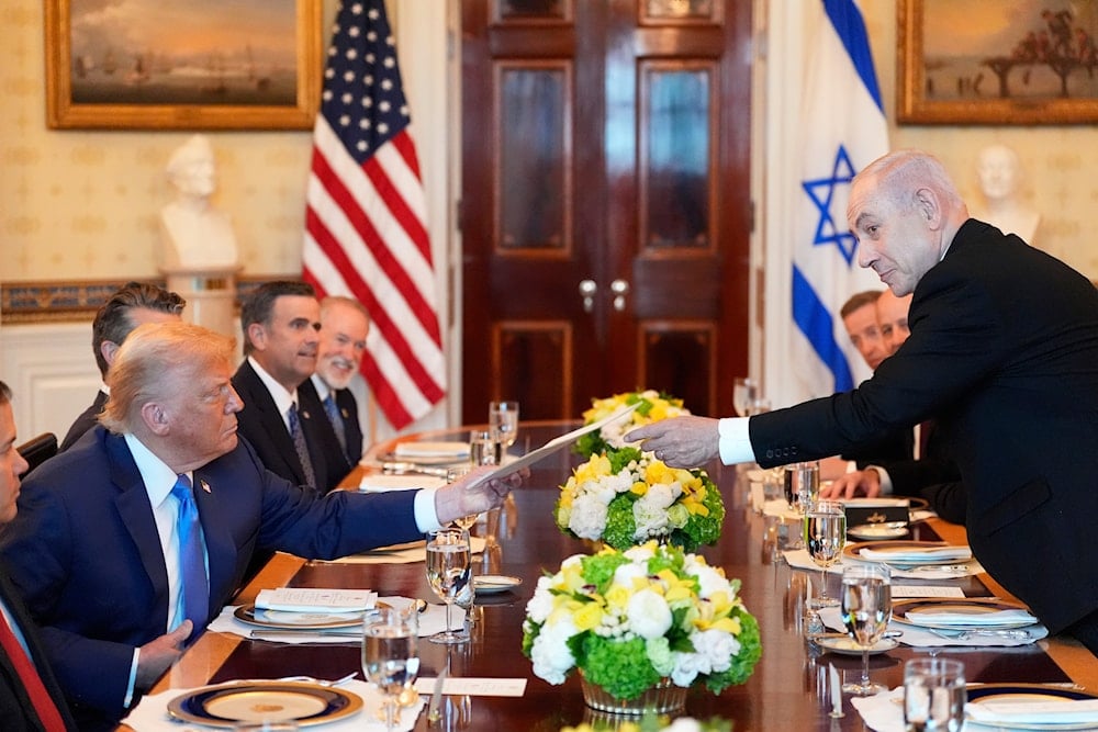 Israeli Prime Minister Benjamin Netanyahu, right, hands President Donald Trump a folder during a meeting in the Blue Room of the White House, Monday, July 7, 2025, in Washington (AP)