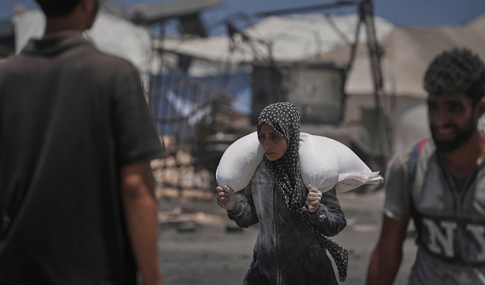 Iman Shabat, a mother of five carries a sack of flour unloaded from a humanitarian aid convoy that reached Gaza City from the northern Gaza Strip, Tuesday, July 22, 2025. (AP)