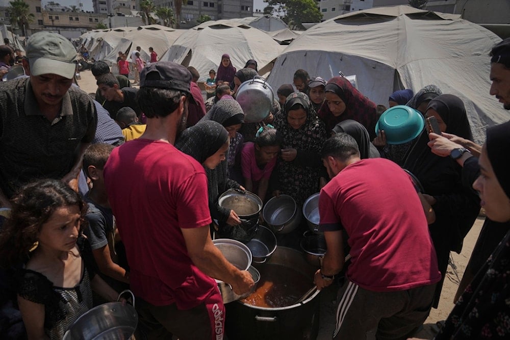 Displaced Palestinians receive donated food at a community kitchen in Gaza City, northern Gaza Strip, Tuesday, July 22, 2025 (AP)