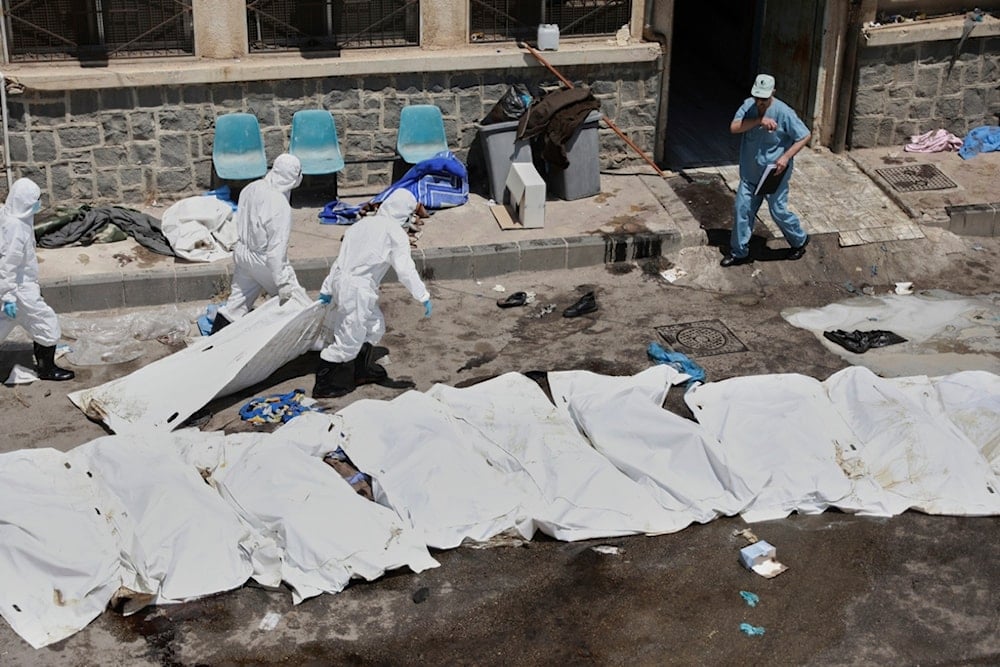 Morgue workers place the bodies of unidentified people killed during clashes between Bedouin clans and Druze fighters into plastic bags outside the National Hospital in Sweida, Syria, Monday, July 21, 2025 (AP)  