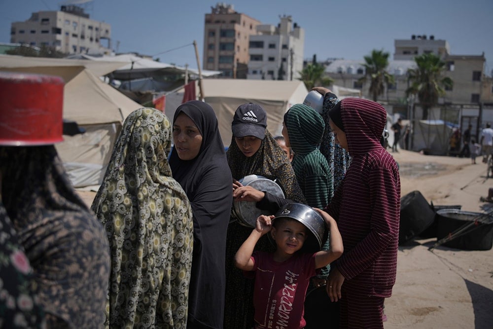 Displaced Palestinians wait for donated food at a community kitchen in Gaza City, northern Gaza Strip, Tuesday, July 22, 2025 (AP)