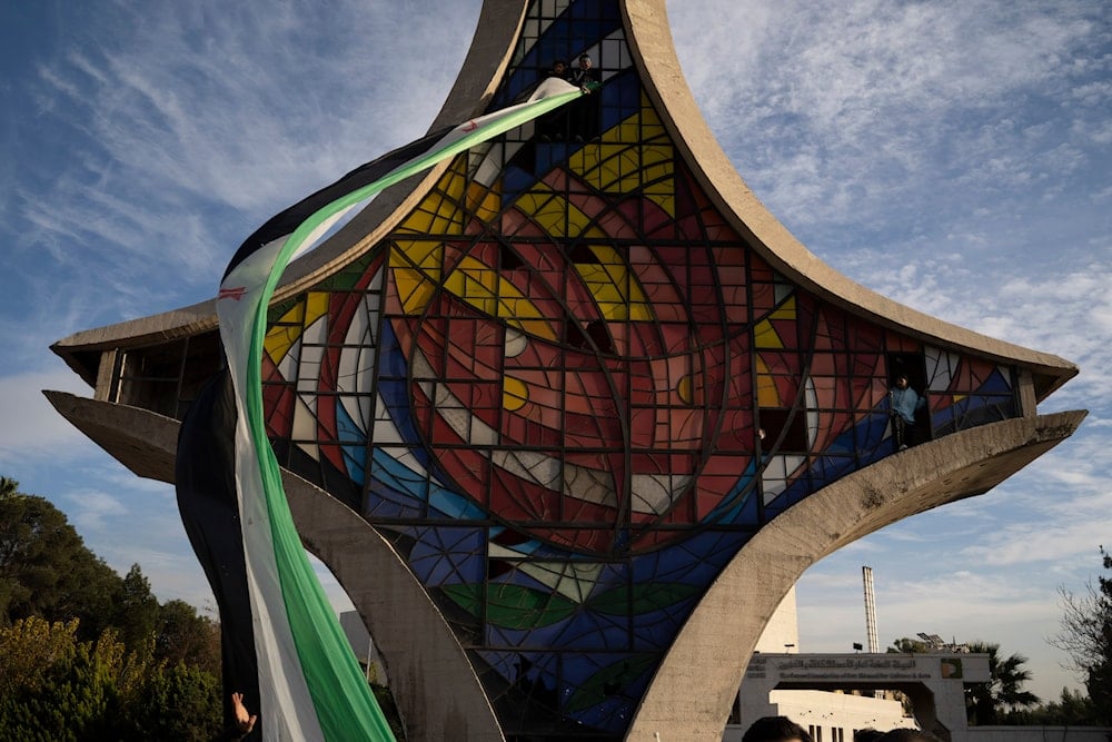 People hold a giant Syrian opposition flag at the Damascene Sword monument Thursday, Dec. 12, 2024. (AP)