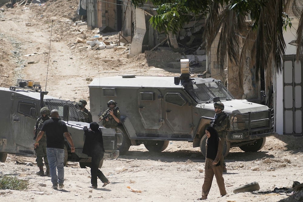 Israeli soldiers speak with Palestinians in the West Bank refugee camp of Tulkarm while residents evacuate as the Israeli military continues its operations ahead of planned home demolitions, Sunday, July 6, 2025 (AP)