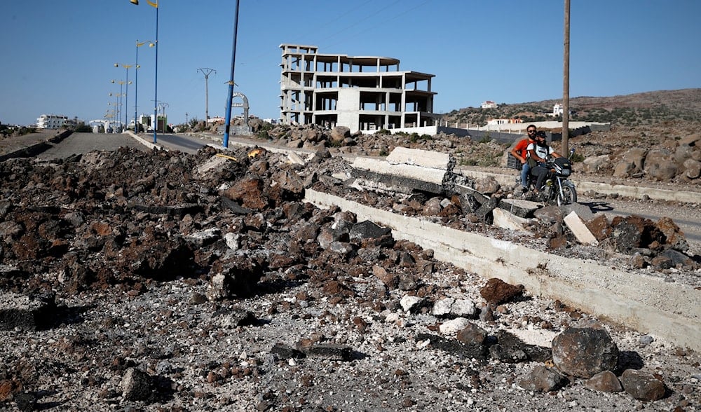 Druze militiamen ride a motorcycle past the site of an Israeli strike last week on the main road outside the town of Sweida, Syria, Friday, July 25, 2025. (AP)