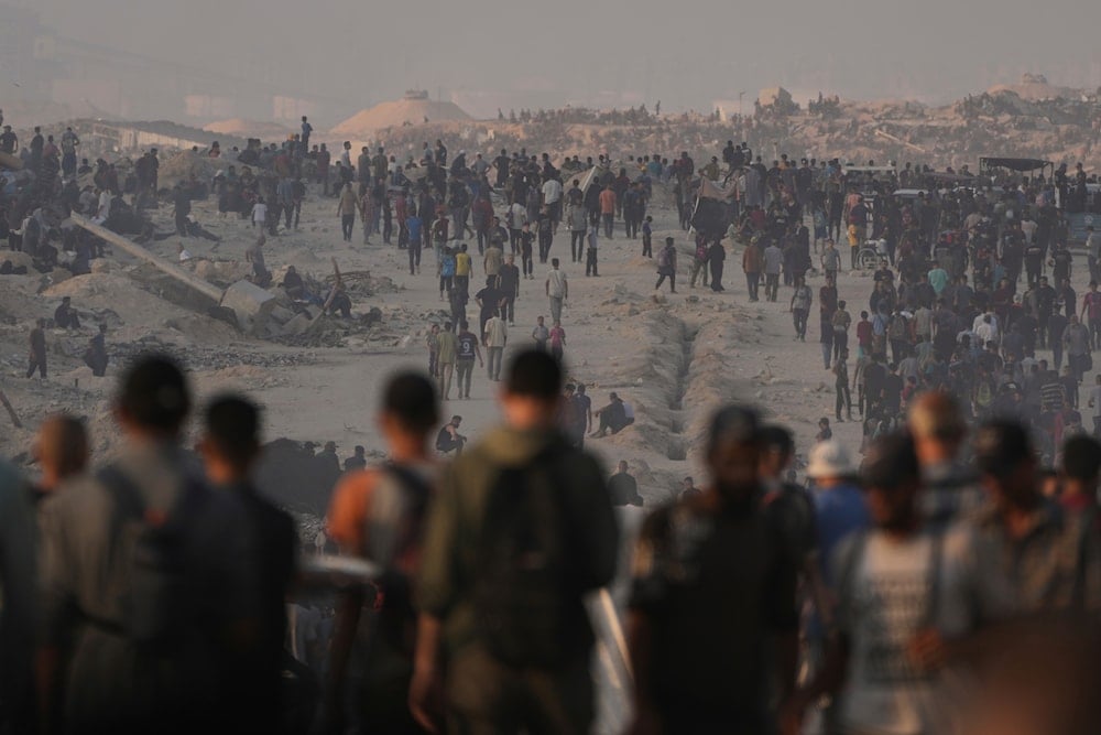 Palestinians walk along a road toward an area in the northern Gaza Strip where trucks are entering with humanitarian aid, in Gaza City, on July 25, 2025. (AP Photo/Abdel Kareem Hana)