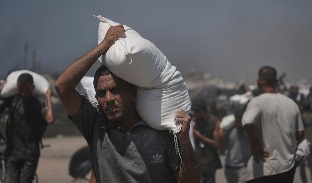 Palestinians carry sacks of flour unloaded from a humanitarian aid convoy that reached Gaza City from the northern Gaza Strip, Sunday, July 27, 2025. (AP)