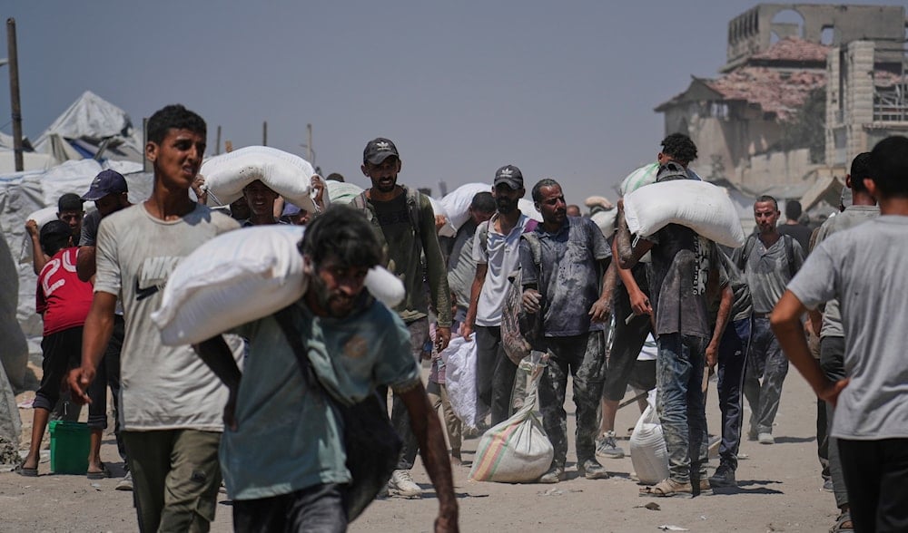 Palestinians carry sacks of flour unloaded from a humanitarian aid convoy that reached Gaza City from the northern Gaza Strip, Sunday, July 27, 2025. (AP)