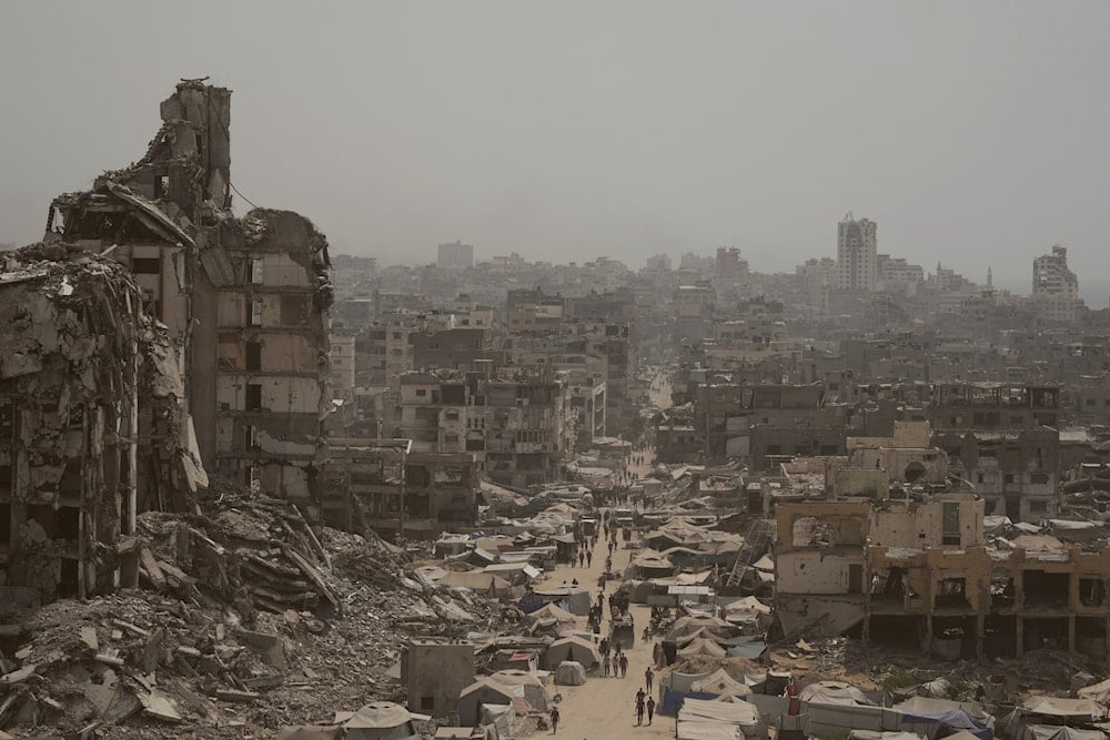 People walk along a street lined with destroyed buildings following Israeli bombardments during the Israeli war on Gaza, Occupied Palestine Tuesday, July 29, 2025 (AP)