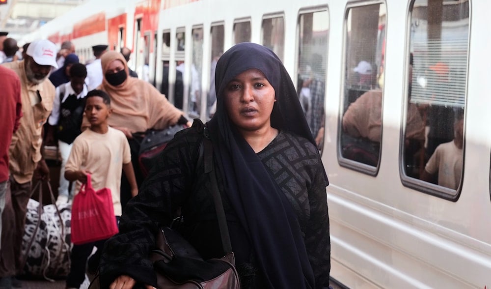 A Sudanese woman, who was driven from her home and is now returning, prepares to enter her train to Aswan at Cairo's Ramses railway station, Egypt, Monday, July 21, 2025. (AP)