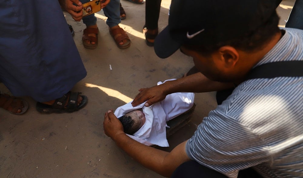 Tamer Qeishtah prepares for burial the body of his niece, who died hours after being delivered by emergency caesarean section to her seven-months pregnant mother, killed in an overnight Israeli airstrike on Khan Younis, July 28, 2025. (AP)