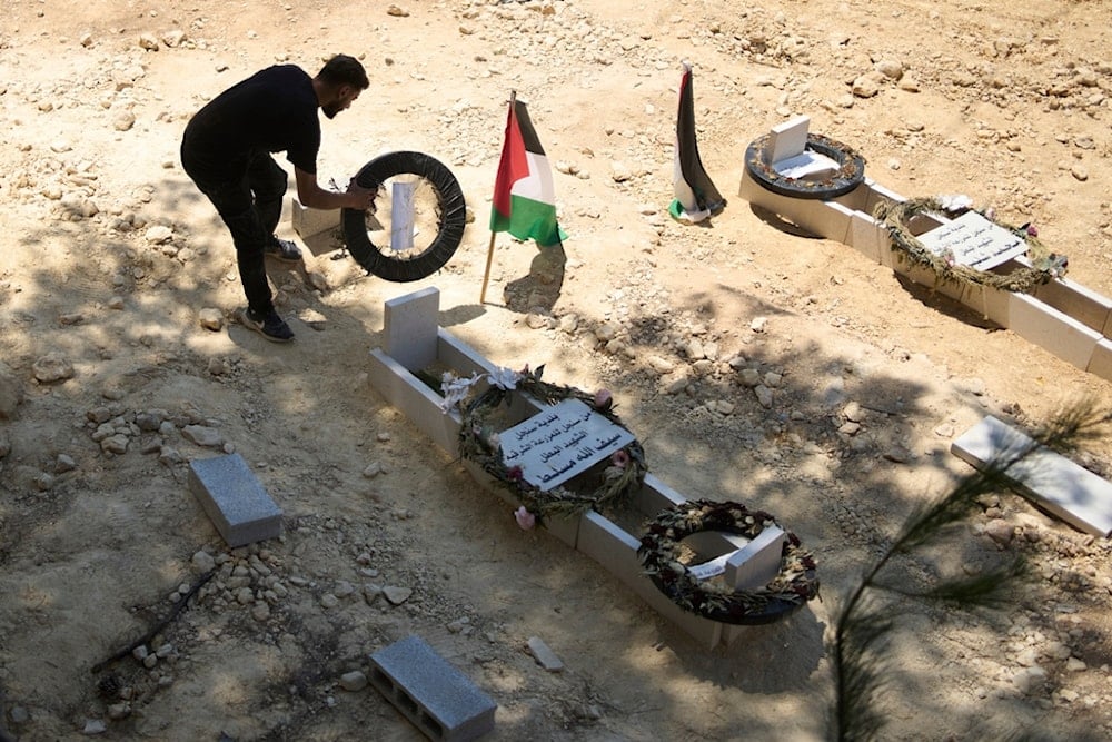On Monday, July 21, 2025, a man tidies the graves of Palestinian-American Sayfollah Musallet, left, and Mohammed al-Shalabi, both of whom were killed by Israeli settlers in the West Bank town of Al Mazra al-Sharqiya (AP) 