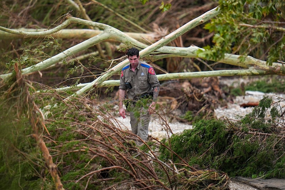 A Texas Department of Public Safety official combs through the banks of the Guadalupe River near Camp Mystic after a flash flood swept through the area Saturday, July 5, 2025, in Hunt, Texas (AP)
